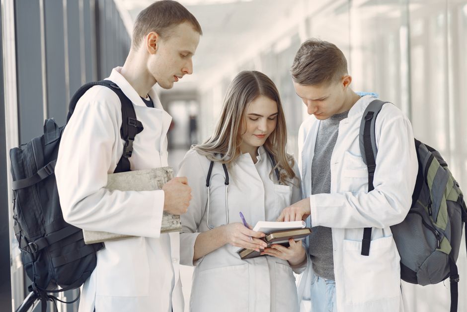 Medical students gather around a table reviewing materials and collaborating during a small group session.